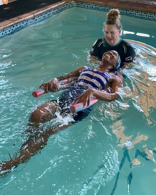 Adult learner relaxing into a supported back-float during a Kiddies Aqua adult swimming lesson