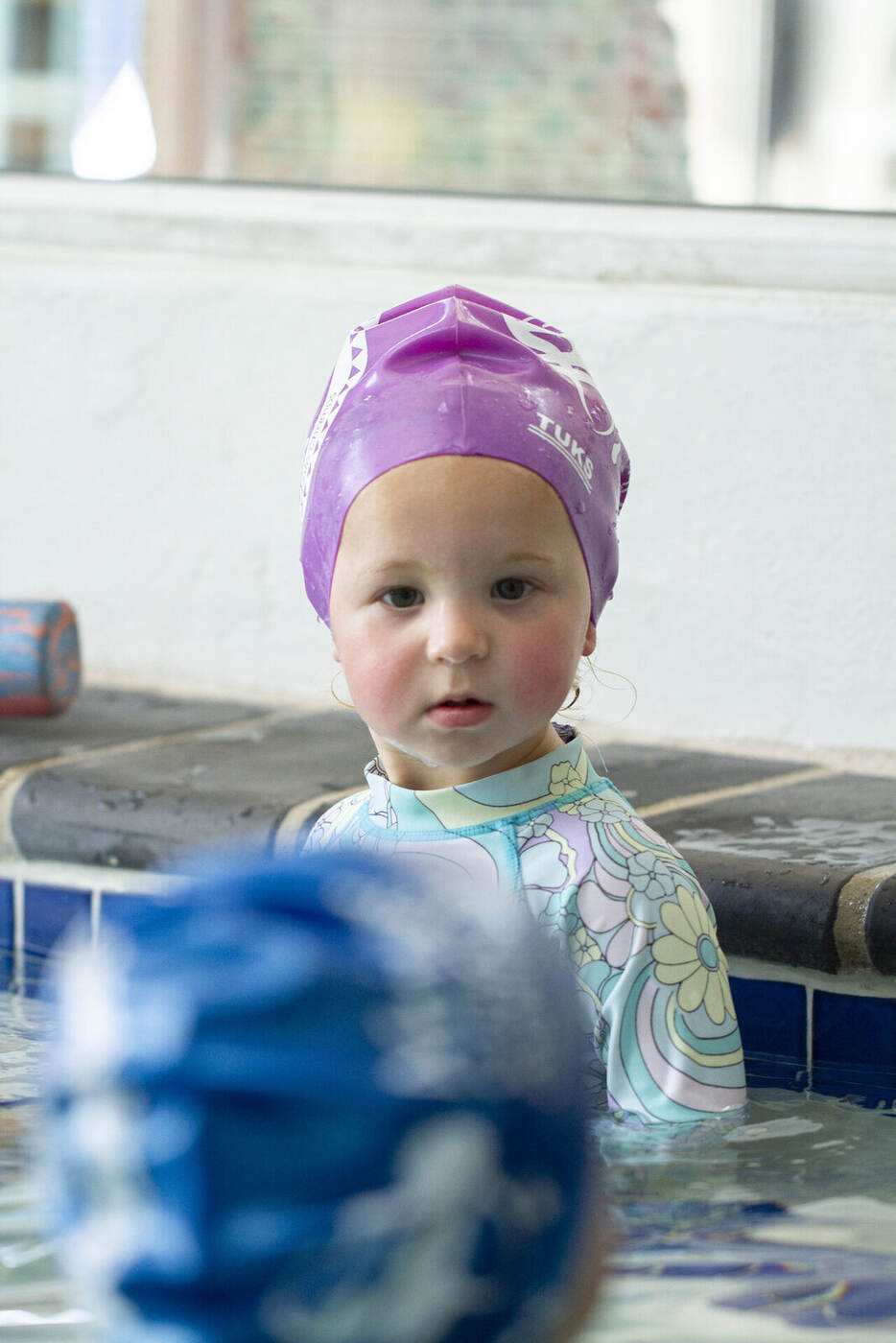 Toddler wearing a TUKS swim cap during a Kiddies Aqua Learn-to-Swim lesson