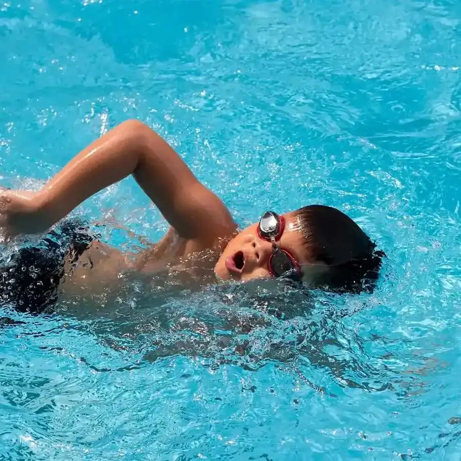 Young swimmer practising freestyle breathing technique with goggles during a stroke-correction lesson