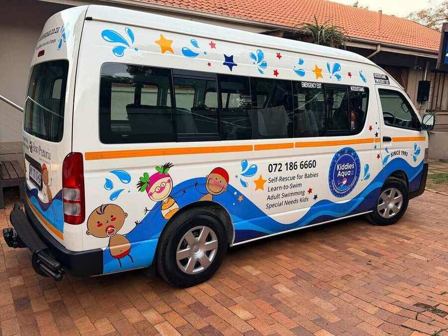 A branded Kiddies Aqua swim-school bus listing its programmes — Self-Rescue for Babies, Learn-to-Swim, Adult Swimming and Special Needs Kids