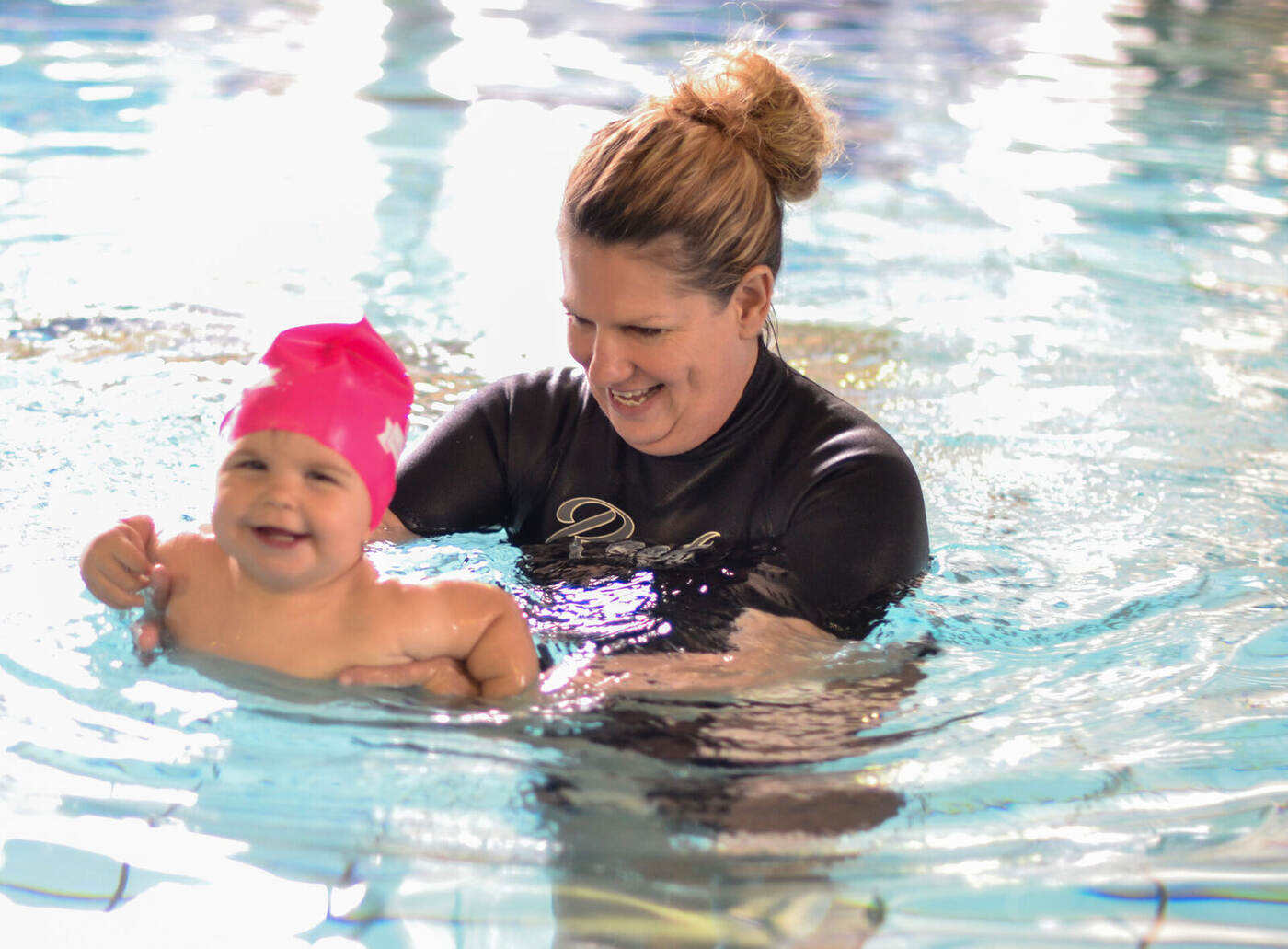 Kiddies Aqua instructor gently guiding a baby through a back-float exercise