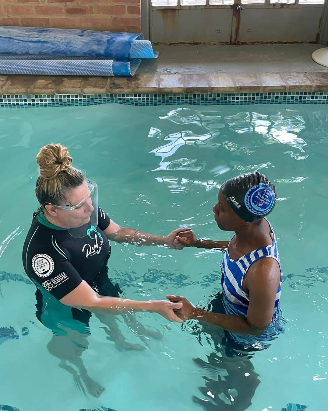 Kiddies Aqua instructor guiding an adult learner through a confidence exercise in the shallow end