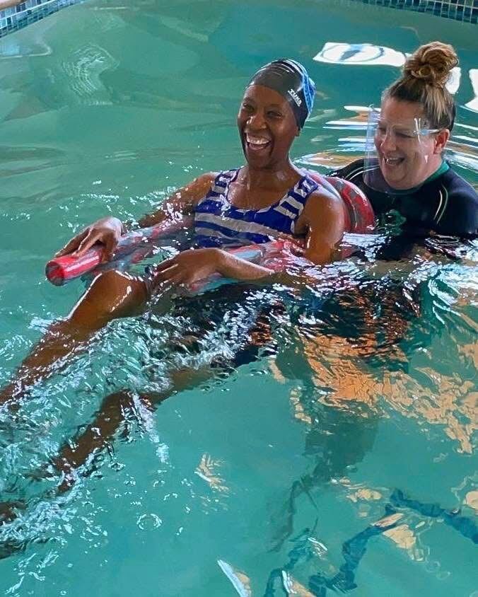 Adult swimmer laughing alongside her Kiddies Aqua instructor during an adult swimming lesson