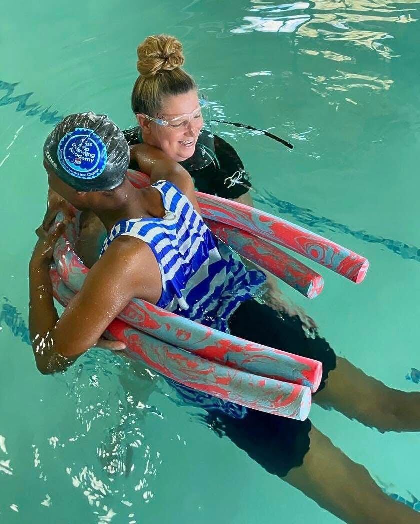 Kiddies Aqua instructor supporting an adult learner with pool noodles during a one-on-one adult swimming lesson